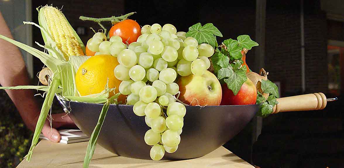 Foto 4: Luxe fruitmand 'Wok'. Zijaanzicht. Wok met daarin biologisch fruit en groenten van het seizoen. Ziet er zeer verzorgd uit.